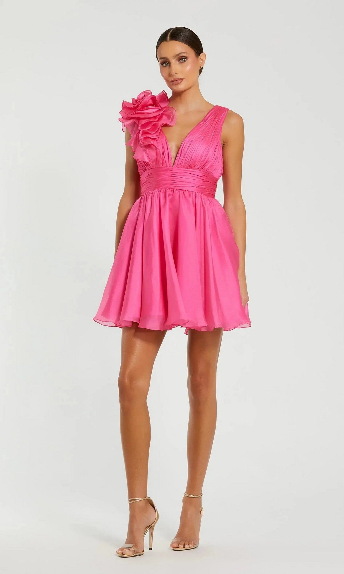A woman wears the Mac Duggal 48952 Ruffle Short White Party Dress, featuring a sleeveless design, deep V-neck, and bold one-shoulder ruffle, styled with nude heels—ideal for semi-formal or party occasions.